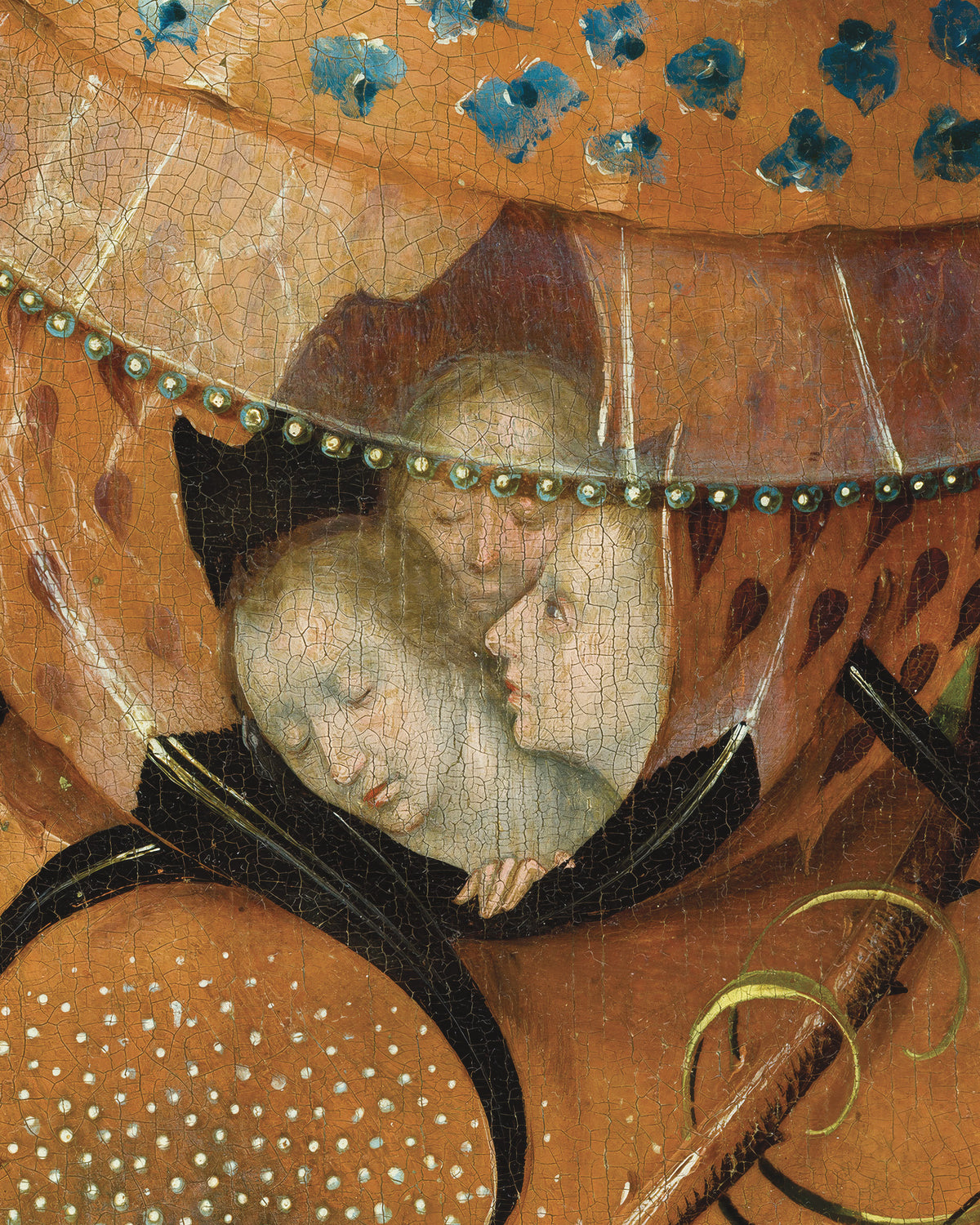 Gros plan d’une scène peinte montrant deux visages pâles sous un grand dais orange orné de motifs décoratifs bleus et bordé de noir.