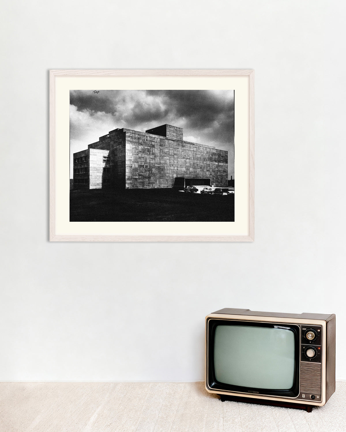 Affiche « Un bâtiment en béton sous l’orage », avec un cadre en bois blanc